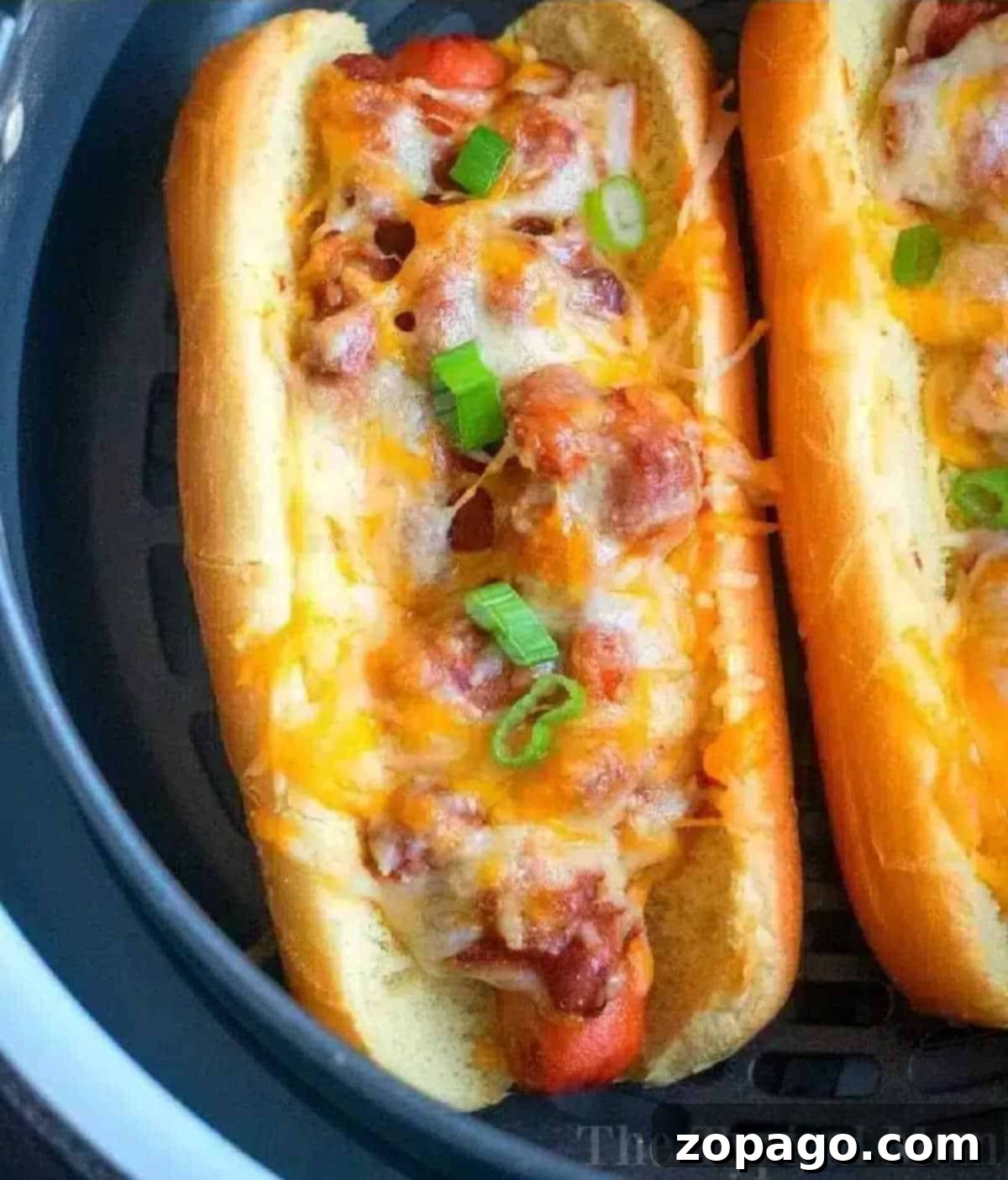Perfectly Crispy Air Fryer Hot Dogs 2 An air fryer hot dog topped with chili, melted cheese, and chopped green onions in a toasted bun.