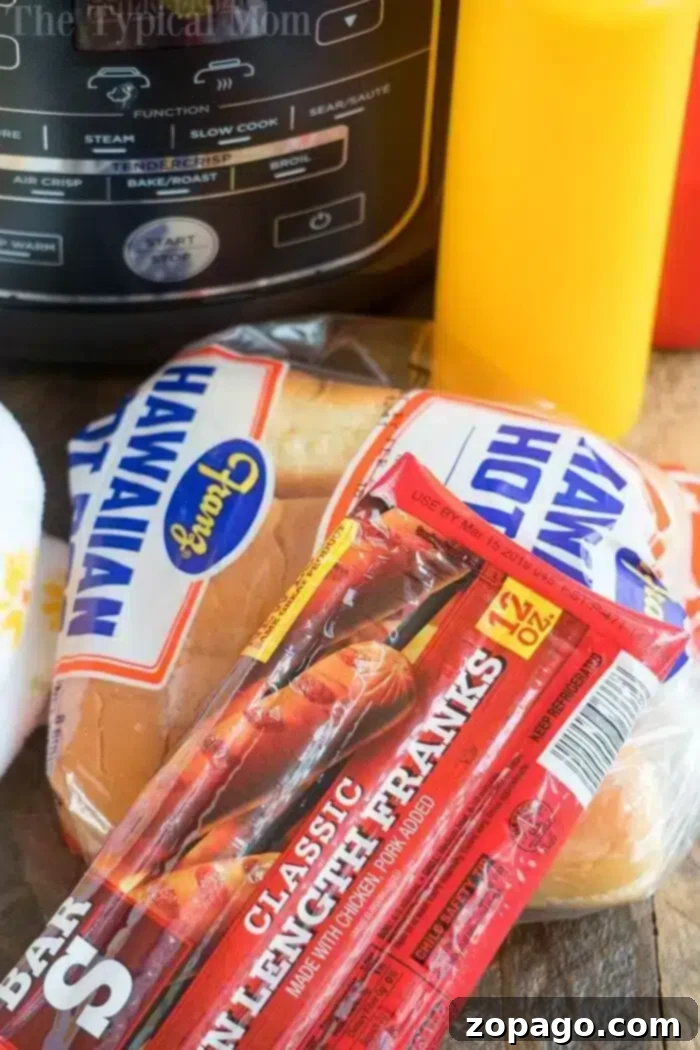 Perfectly Crispy Air Fryer Hot Dogs 4 A package of classic lunch franks sits on a wooden surface next to a pack of Hawaiian hot dog buns. Behind them, an air fryer is ready for perfectly crispy hot dogs, and a yellow condiment bottle is partially visible.