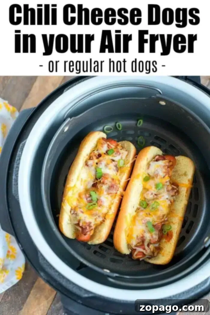 Perfectly Crispy Air Fryer Hot Dogs 8 An air fryer contains two chili cheese topped hot dogs on buns. The hot dogs are garnished with chopped green onions and melted cheese. The text above the image reads, "Chili Cheese Dogs in your Air Fryer - or regular air fryer hot dogs -".
