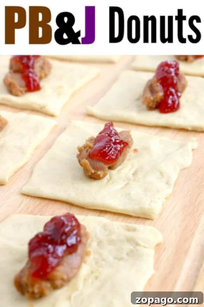 A close-up of unbaked peanut butter and jelly doughnuts, showcasing their classic two-tone filling, on a wooden surface.