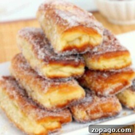 A stack of sugar-coated, flaky pastry sticks on a white plate offers a delightful crunch reminiscent of peanut butter and jelly donuts.