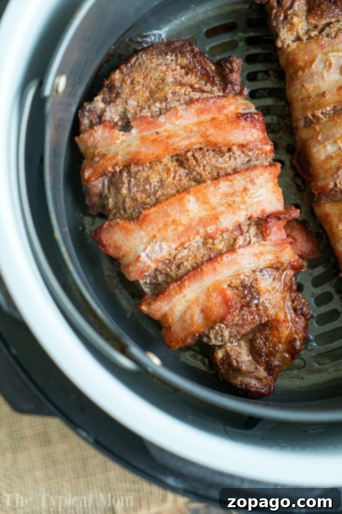 Ninja Foodi Steak: Bacon Wrapped & Dry Rubbed Savor the irresistible taste of bacon-wrapped steak cooked to perfection in an air fryer basket, exemplifying the same juicy tenderness youd expect from a well-crafted air fryer steak.