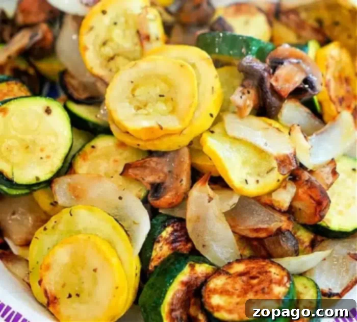 Crispy and Healthy Ninja Foodi Air Fryer Mixed Vegetables A vibrant dish of perfectly air-fried mixed vegetables, including sautéed yellow squash, zucchini, mushrooms, and onions. The sliced veggies are beautifully seasoned and show a delightful golden-brown crispness from the cooking process, elegantly presented on a plate.