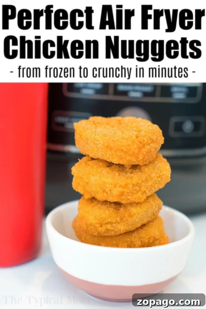 Frozen to perfect air fryer frozen chicken nuggets in your Ninja Foodi or any other brand so they're tender inside and really crispy on the outside. This is it! #airfryer #airfryerrecipes #ninjafoodi #chickennuggets #chicken #easy #frozen A basket full of perfectly air-fried frozen chicken nuggets, golden and ready to be served.
