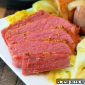 Slices of tender corned beef with cabbage and potatoes grace a white plate, revealing the magic of a Ninja Foodi in transforming this classic dish into a perfectly cooked masterpiece.