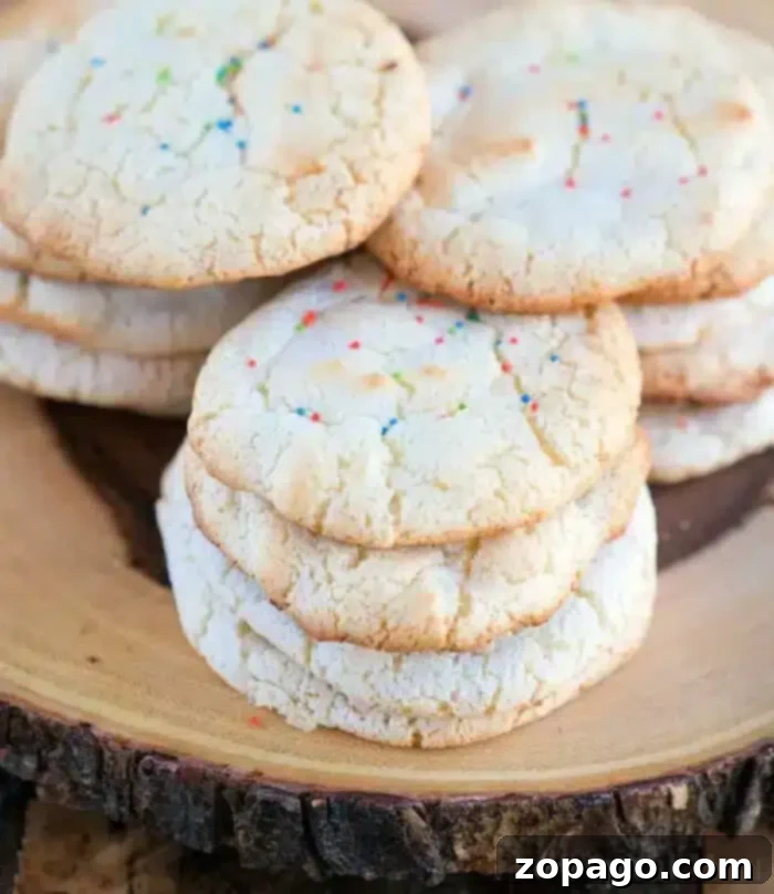 Effortless Angel Food Two-Ingredient Cookies 2 A stack of six sugar cookies made from angel food cake mix with colorful rainbow sprinkles rests invitingly on a wooden platter.
