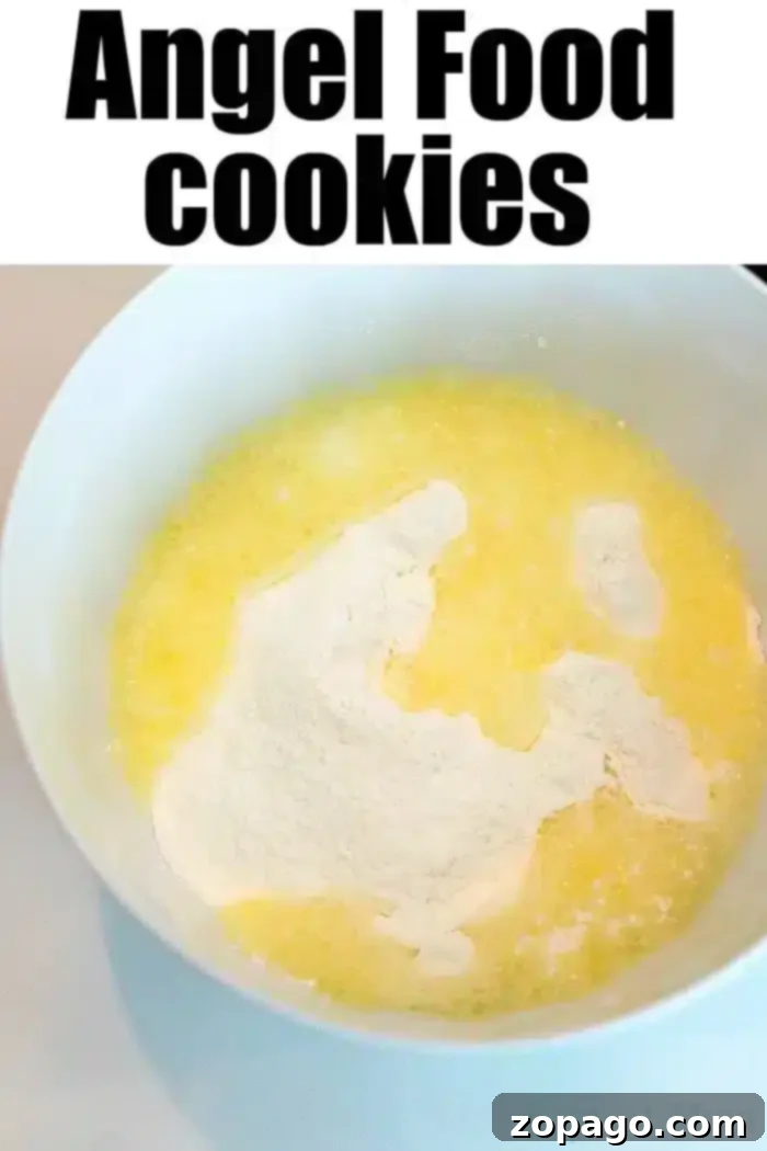 Effortless Angel Food Two-Ingredient Cookies 3 A white mixing bowl containing yellow, melted butter and white, powdered ingredients, ready for mixing.