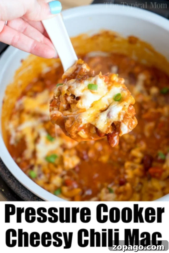 Pressure cooker cheesy chili mac is so good! Packed with flavor and taking only 20 minutes to make in your Instant Pot or Ninja Foodi, you'll love it! #instantpotrecipes #instantpot #thetypicalmom #ninjafoodirecipes #ninjafoodi #chilimac #cheesy #casserole #pasta A close-up of a Ninja Foodi pot brimming with creamy, cheesy chili mac, highlighting the rich texture and vibrant colors.