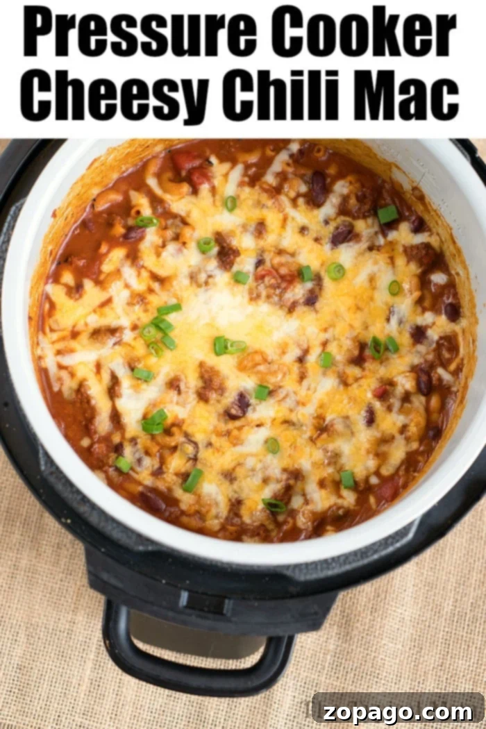 Ninja Foodi cheesy chili mac is so good! Packed with flavor and taking only 20 minutes to make in your Instant Pot or Ninja Foodi, you'll love it! #instantpotrecipes #instantpot #thetypicalmom #ninjafoodirecipes #ninjafoodi #chilimac #cheesy #casserole #pasta A top view of a ninja foodi reveals a delicious batch of cheesy chili mac, perfectly garnished with chopped green onions.