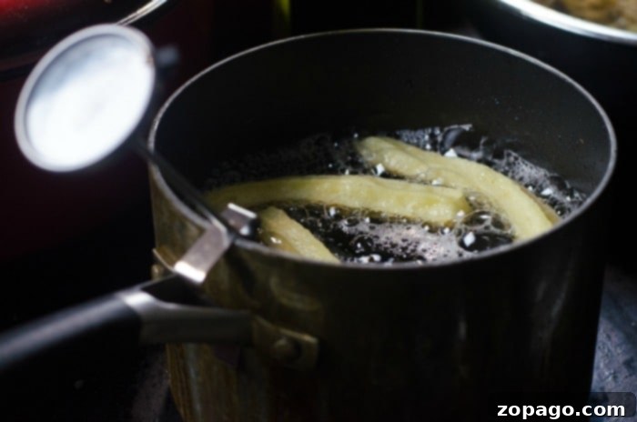 Delicious Homemade Churros 3 Churros sizzling deliciously in a pot of hot oil on the stovetop, illustrating the process of crafting the best homemade churros recipe.