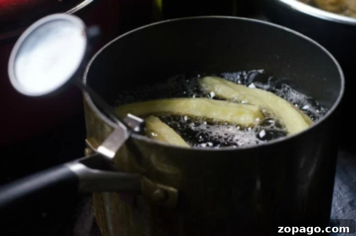 Delicious Homemade Churros 3 Close-up shot of churros sizzling and turning golden in a pot of hot oil, illustrating the process of creating the best homemade churros recipe.