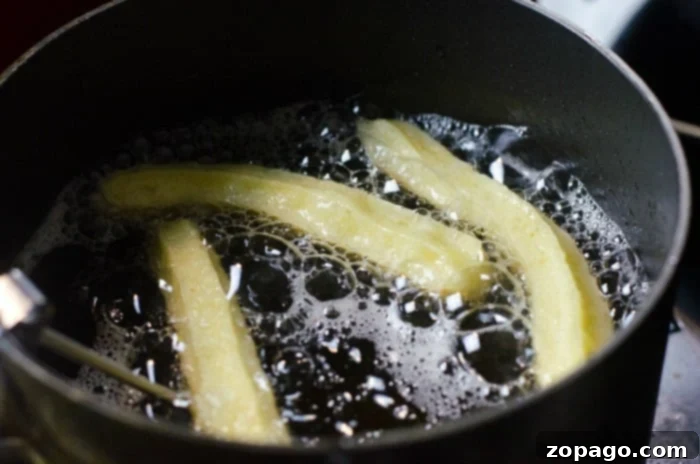 Delicious Homemade Churros 4 Churros frying to a crispy, golden-brown perfection in hot oil within a pan, embodying the ideal texture for the best churros recipe.