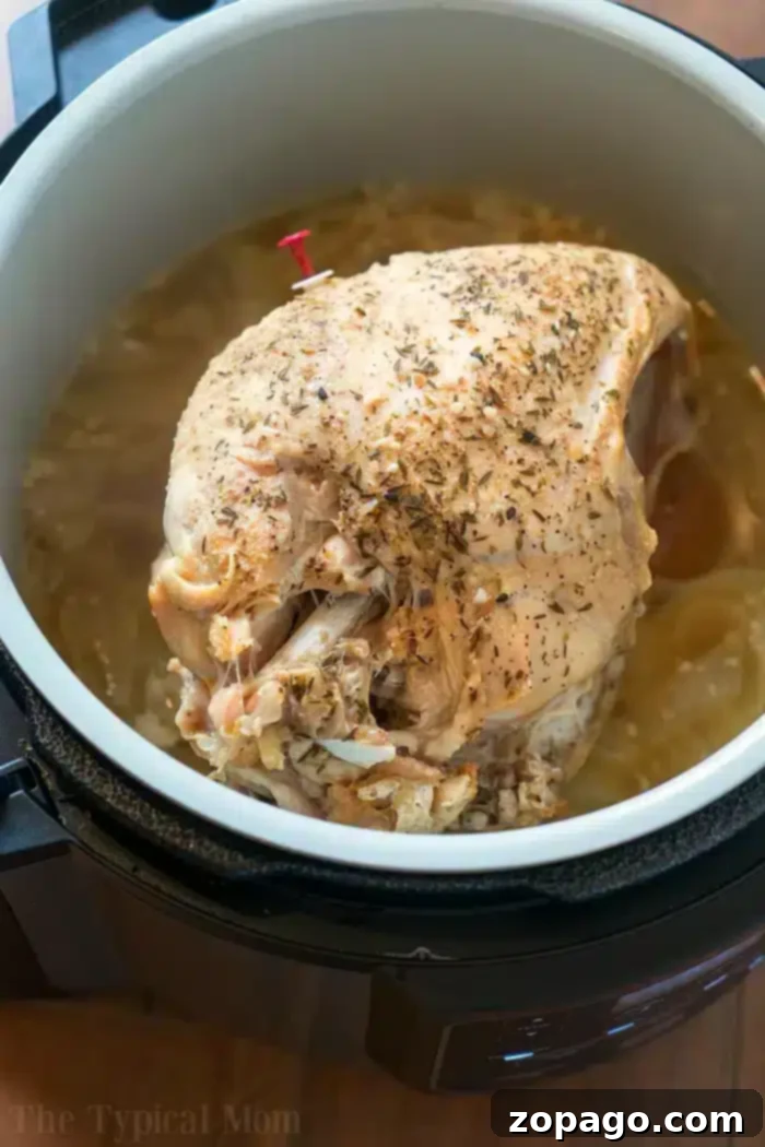 Pressure cooker turkey breast simmers in a Ninja Foodi, perfectly seasoned with herbs and surrounded by savory broth.