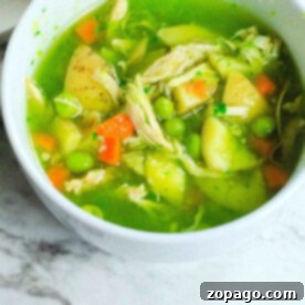 Instant Pot Comfort Soup 7 A comforting bowl of feel better soup, featuring peas, carrots, potatoes, and shredded chicken in a green broth, uses the convenience of an Instant Pot to bring warmth and nourishment to your table. Placed invitingly on a marble surface, it's perfect for those days when you need an extra hug.