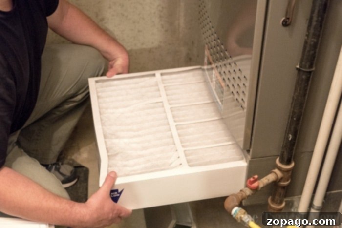 A clean, new air filter being inserted into a home HVAC system, illustrating proper installation.