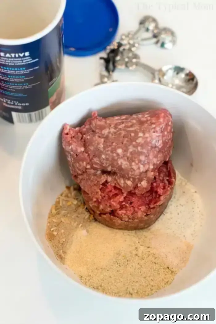 Perfect Ninja Foodi Meatloaf 3 A bowl containing ground meat and various spices ready to become a delicious Ninja Foodi meatloaf. There's a container in the background and a set of measuring spoons.