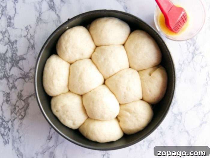 Whip Up Delicious Dinner Rolls 3 Hands gently shaping a portion of yeast dough into a small, perfect ball for dinner rolls.