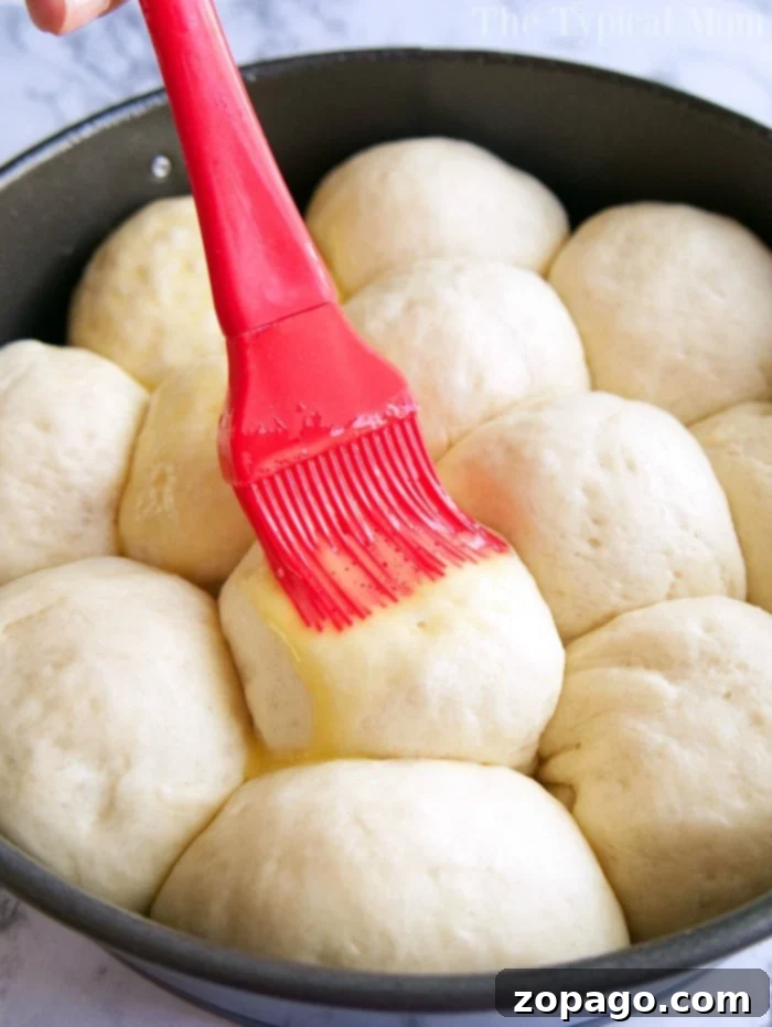 A bountiful display of homemade yeast rolls. A basket overflowing with warm, homemade yeast rolls, garnished with fresh herbs, ready for the table.