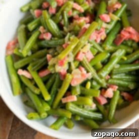 A bowl of sautéed green beans, perfected in the Ninja Foodi, mixed with diced bacon and onions.