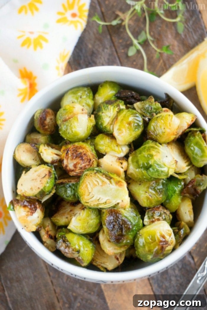 A bowl of roasted Brussels sprouts rests on a table adorned with a floral napkin, perfectly crisped and seasoned from the air fryer, making a delicious and healthy side dish.