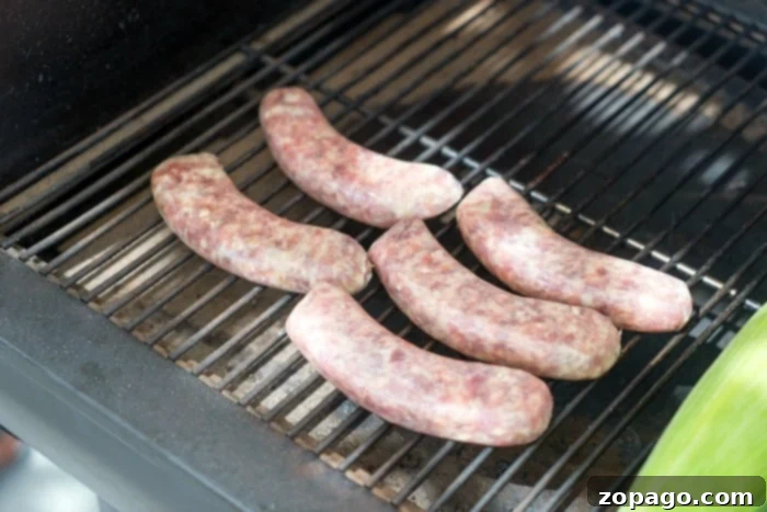 Smoked brats are a delicious lunch or dinner idea you can make in your pellet or electric smoker this week! If you haven't smoked sausage yet, try this! #smokerrecipes #smoked #smoker #sausage #brats #traeger Close-up of a smoked sausage on a cutting board, ready to be sliced