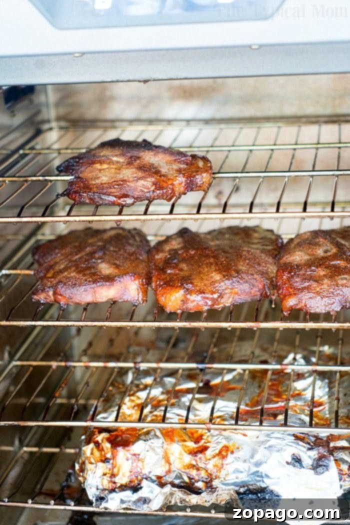 Top Cuts for Incredible Smoked Flavor 5 Smoked pork steaks and pork chops roast in electric smoker, showing an array of delicious smoked meats.