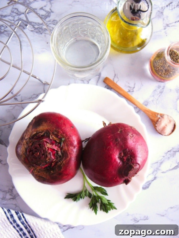 Instant Pot beets are the best vegetable. #instantpot #beets #beetrecipes #instantpotrecipes #pressurecooker #vegetables #healthy Two whole instant pot beets rest on a plate with parsley, accompanied by a glass of water, oil, spices, and a spoon on the marble surface.