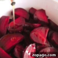 Chopped red beets in a bowl, freshly cooked to perfection using an Instant Pot, are being drizzled with oil.