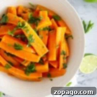 Pressure cooker carrots, sliced and cooked to perfection, are garnished with chopped parsley in a white bowl on a marble surface with lime nearby.