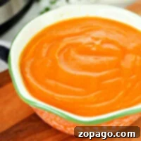 A bowl of creamy, homemade Instant Pot carrot soup garnished with fresh herbs.
