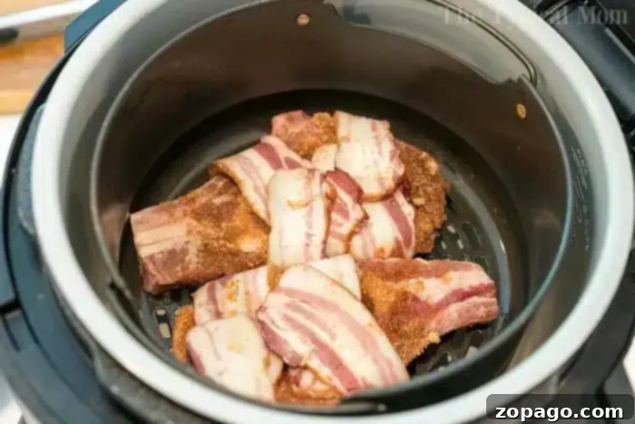 Pork Chops in Bacon Blankets 4 Golden-brown, crispy bacon-wrapped air fryer pork chops served on a plate.