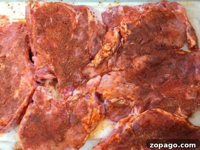 Smoky Grilled Pork Chops 3 Fresh pork chops in a bowl, coated in a rich marinade, waiting to absorb flavors.