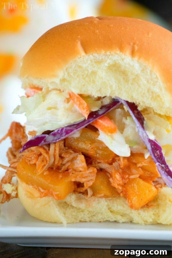 Instant Pot pulled pork sliders. #hawaiian #pulledpork #instantpot A delightful pulled pork sandwich with coleslaw and pineapple, perfect for your July gatherings, crafted effortlessly with Instant Pot magic.