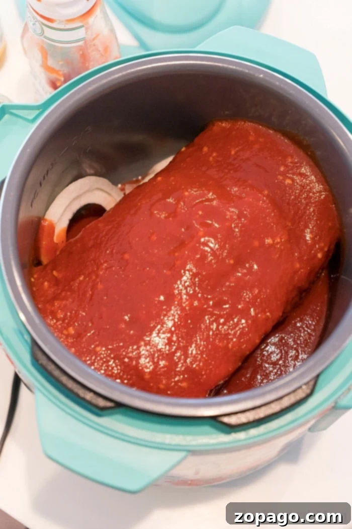 Instant Pot beef recipe with chuck roast. Chuck roast topped with sauce sits deliciously inside a pressure cooker on the countertop, reminiscent of comforting instant pot beef roast recipe.