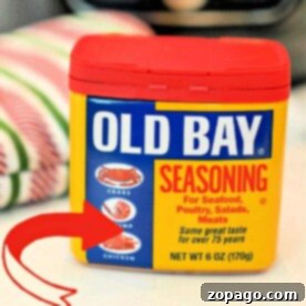 Old Bay Seasoning container showcasing its perfect pairing with seafood, poultry, salads, and meats. A red arrow highlights crab, shrimp, and chicken. Discover how to make Old Bay from scratch to enhance each dish with authentic flavor at home.