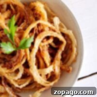 Crispy Fried Onions 8 A bowl of crispy fried onion rings garnished with fresh parsley.