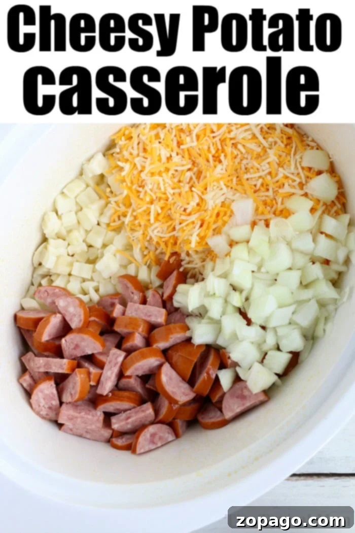 Effortless Slow Cooker Cheesy Hashbrown Bake 4 A delightful close-up of a slow cooker filled with cheesy potatoes, featuring diced frozen potatoes, generous amounts of shredded cheese, finely chopped onions, and savory sliced sausage, all ready to be cooked to perfection.