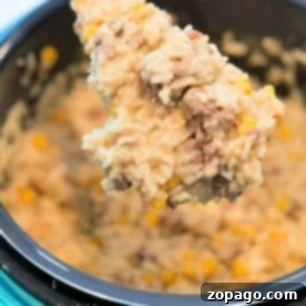 Spoonful of creamy rice, ground beef, and corn from an instant pot hamburger casserole, highlighting its rich texture.