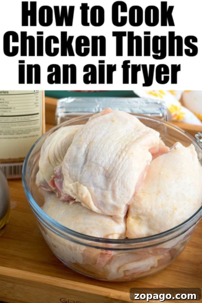 Effortless Chicken Thigh Dinners 5 Raw, bone-in chicken thighs rest in a glass bowl against a backdrop of various cooking ingredients and an air fryer guide.