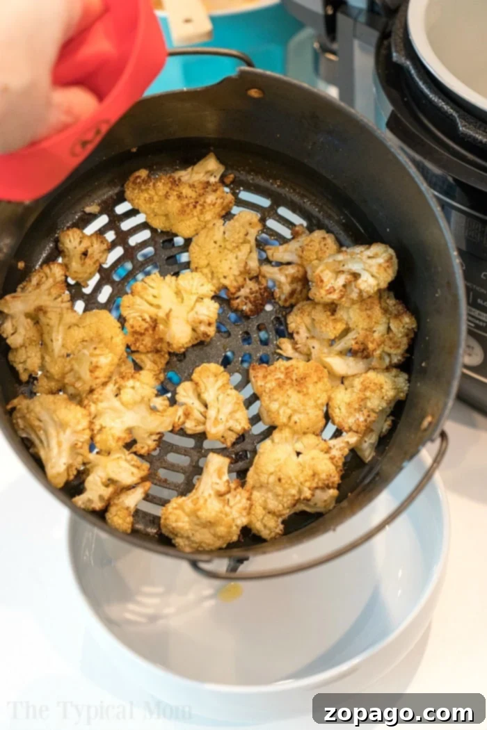How to make cauliflower in air fryer. #airfryer Close-up of golden-brown air-fried cauliflower florets scattered in an air fryer basket, ready to be served as a healthy snack or side.