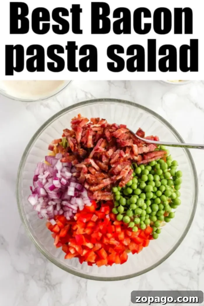 Smoky Bacon Pasta Salad 4 A glass bowl filled with chopped ingredients for a bacon pasta salad: crispy bacon, red onions, peas, and red bell peppers. Above the bowl, text reads "Best Bacon Pasta Salad." The background is a pristine white marble surface.