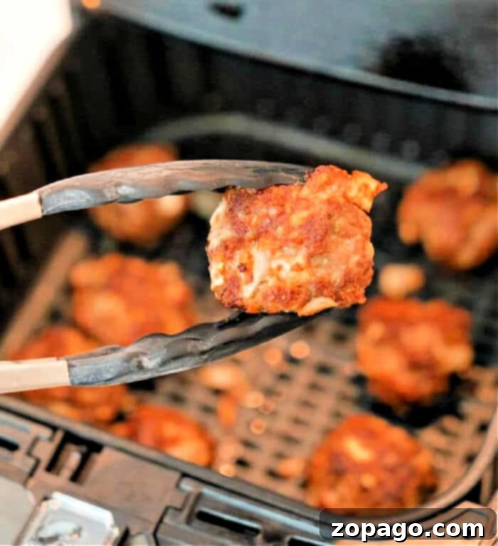 Easy Air Fryer Meatballs 2 Crispy Ground Beef Meatballs in Air fryer basket, perfectly browned and ready to serve.
