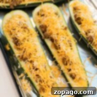 Stuffed Zucchini Tacos 5 Zucchini taco boats stuffed with seasoned ground meat and topped with shredded cheese rest invitingly on a foil-lined tray.