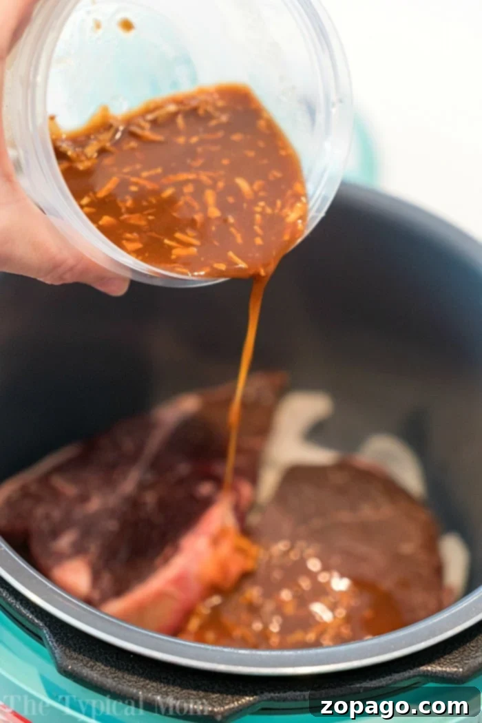 Instant Pot Steakhouse Steak 3 Close-up of a perfectly cooked steak in an Instant Pot, surrounded by tender potatoes and onions, glistening with savory gravy.