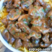 Tender Beef Bites, Effortlessly Made in Your Instant Pot 6 Instant Pot beef tips stroganoff with mushrooms, served over egg noodles and garnished with chopped herbs in a white bowl.