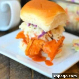 Slow Cooker Buffalo Chicken Sliders 5 A delicious crockpot buffalo chicken slider with coleslaw graces a square white plate.