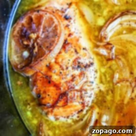 Slow Cooker Lemon Pepper Chicken 8 Close-up of crockpot lemon pepper chicken with caramelized onions simmering in a savory broth.