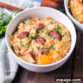A bowl of savory instant pot sausage and rice casserole topped with herbs rests on a wooden table, accompanied by a gray napkin.