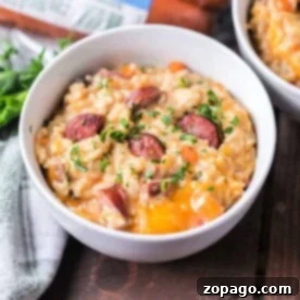 A bowl of savory instant pot sausage and rice casserole topped with herbs rests on a wooden table, accompanied by a gray napkin.