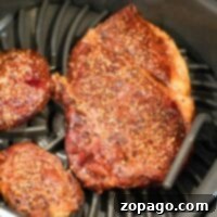 Two seasoned steaks are being expertly cooked in the Ninja Foodi Grills air fryer basket, ensuring juicy perfection with every bite.